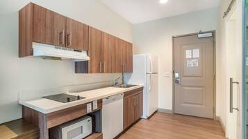A compact kitchen with wooden cabinets, a built-in microwave, a dishwasher, and a refrigerator.