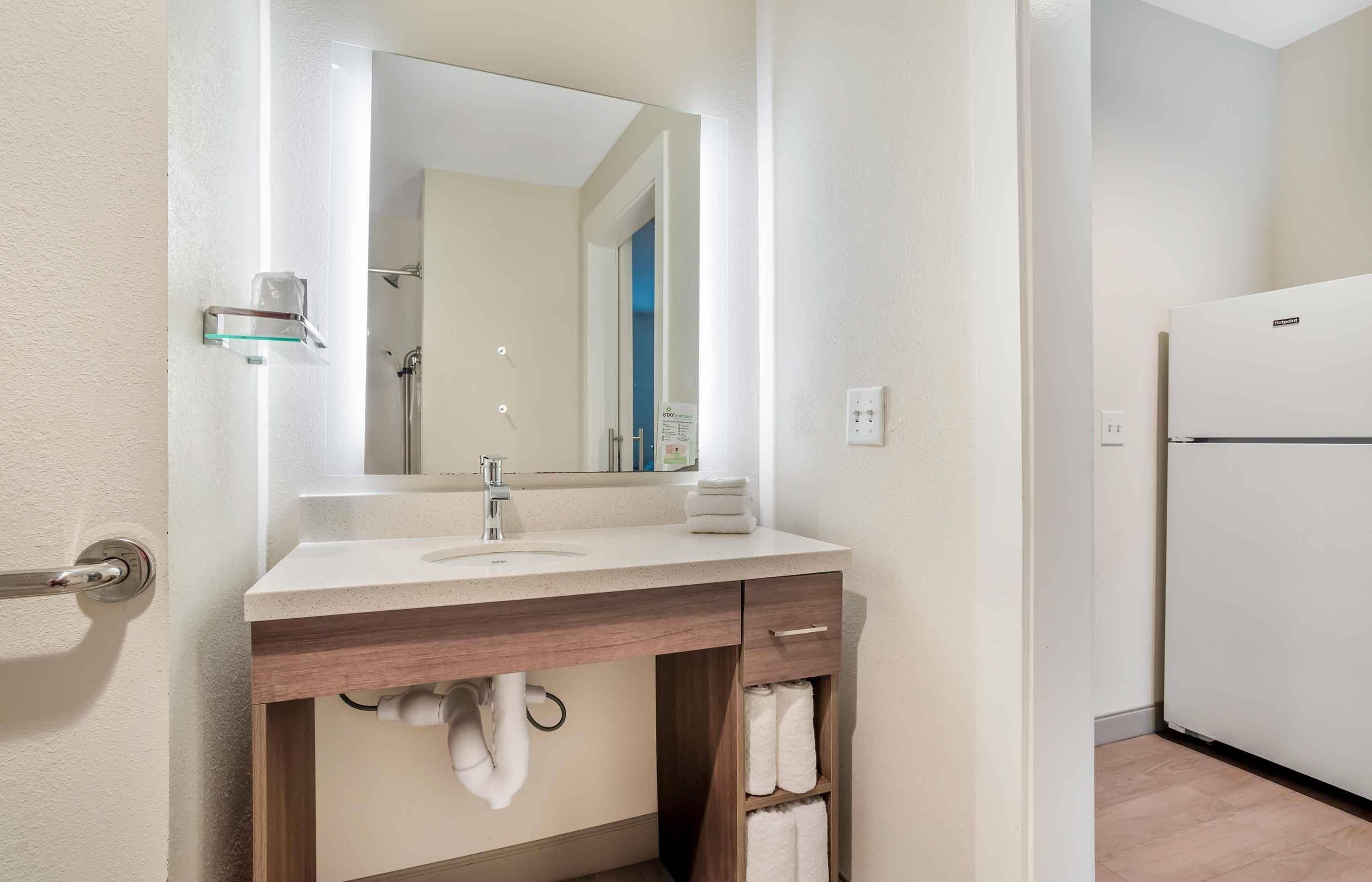 A bathroom with a sink, mirror, towel rack, and a shower.