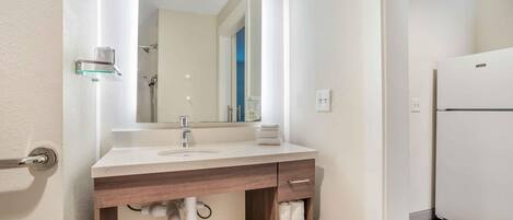 A bathroom with a sink, mirror, towel rack, and a shower.