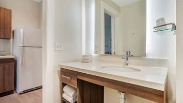 A modern bathroom with a sink, mirror, and towel rack.