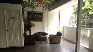 Una habitación con una puerta blanca, dos sillones con estampado, una mesita y un cuadro en la pared.