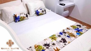 Et hotelværelse med seng, puder, et natbord med telefon og et spejl.