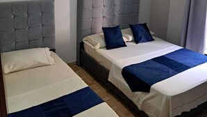 Et hotelværelse med to senge, hver med gråt sengegavl og hvide sengetøj. Der er en loftlampe over sengene.