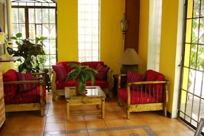 A room with yellow walls, red sofas, a wooden coffee table, and a potted plant.