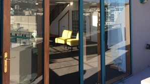 A modern building with a glass door leading to a balcony with yellow chairs and a view of the cityscape. - U Suites on Courtenay (Wellington)