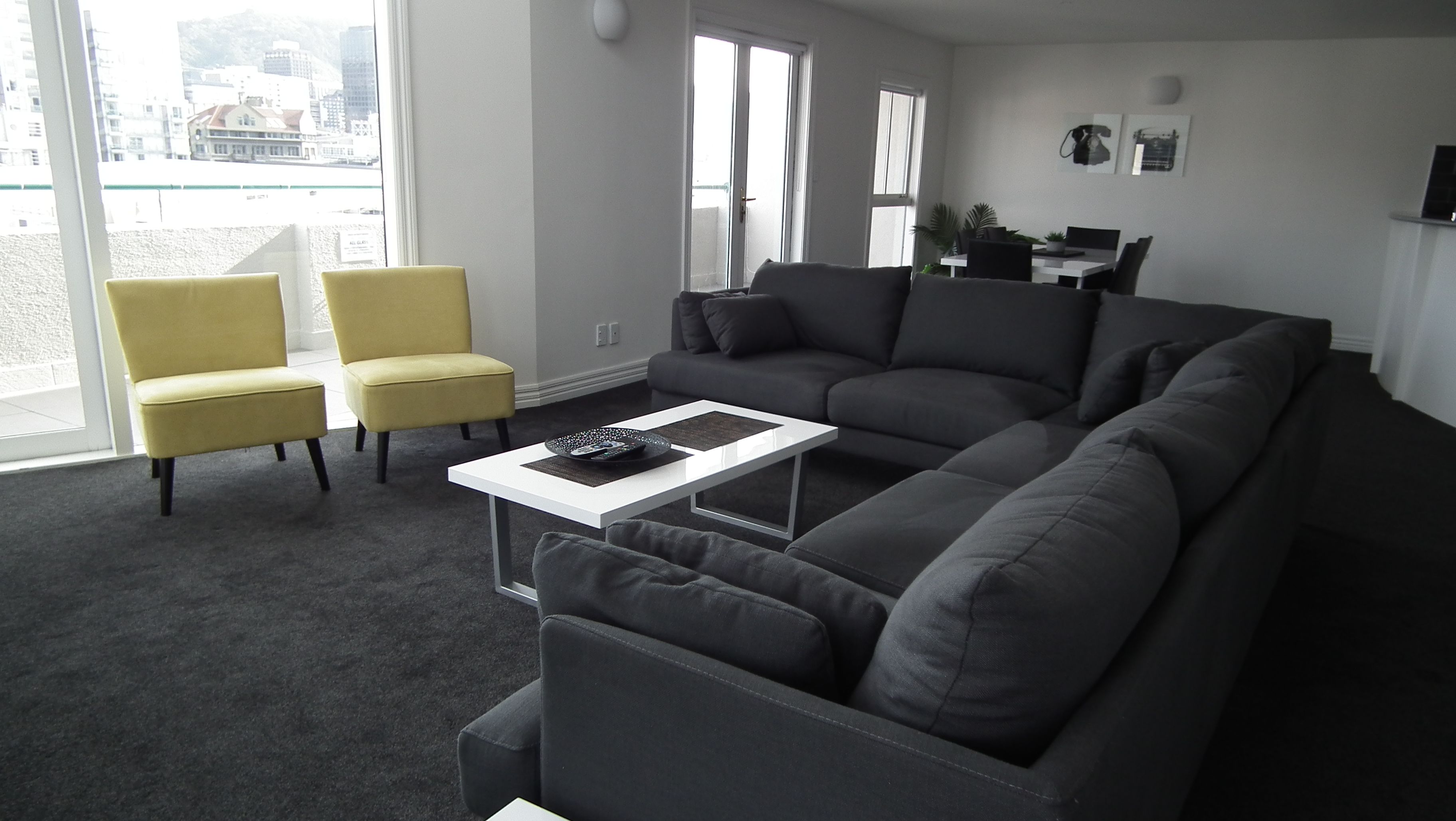 A modern living room with a grey sofa, a yellow armchair, and a white coffee table.