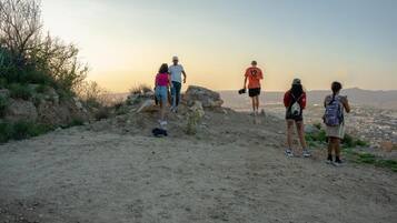 A group of people on a dirt path with a view of a city in the distance.