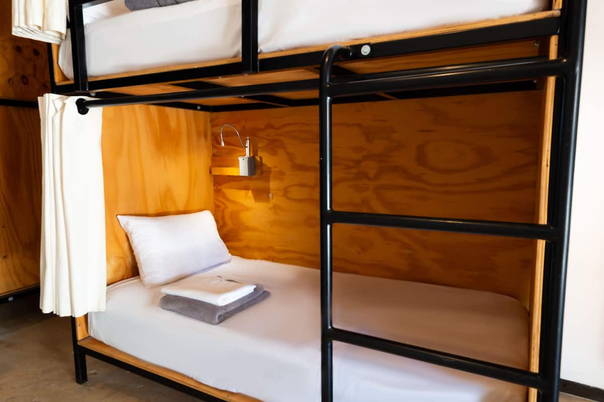 Una cama litera con cabecera de madera y una mesita de noche con lámpara.