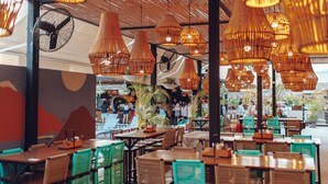 An indoor dining area with multiple tables and chairs, overhead wicker lamps, and a fan on the ceiling. - Mayan Monkey Los Cabos | Social Hotel (Cabo San Lucas)