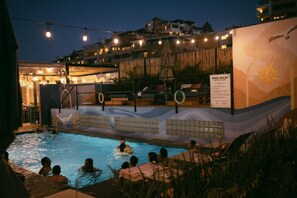 Un espace autour de la piscine comprenant des chaises longues et un panneau indiquant les règles à respecter.