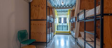 A corridor with bunk beds, a green chair, and a visible bathroom with a sink.