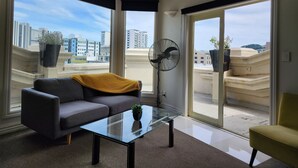 A modern living room with a glass coffee table, a grey sofa, and a yellow throw blanket. - U Suites on Manners (Wellington)