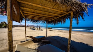 A beachside hut with a thatched roof, two lounge chairs, and a small table. - Casa Safran (Los Organos)