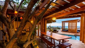 A wooden outdoor dining area with benches and a poolside view. - Casa Safran (Los Organos)