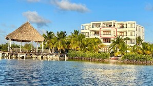 A beachfront hotel with a thatched-roof structure, palm trees, and a clear view of the ocean. - Brahma Blue Resort (San Pedro)