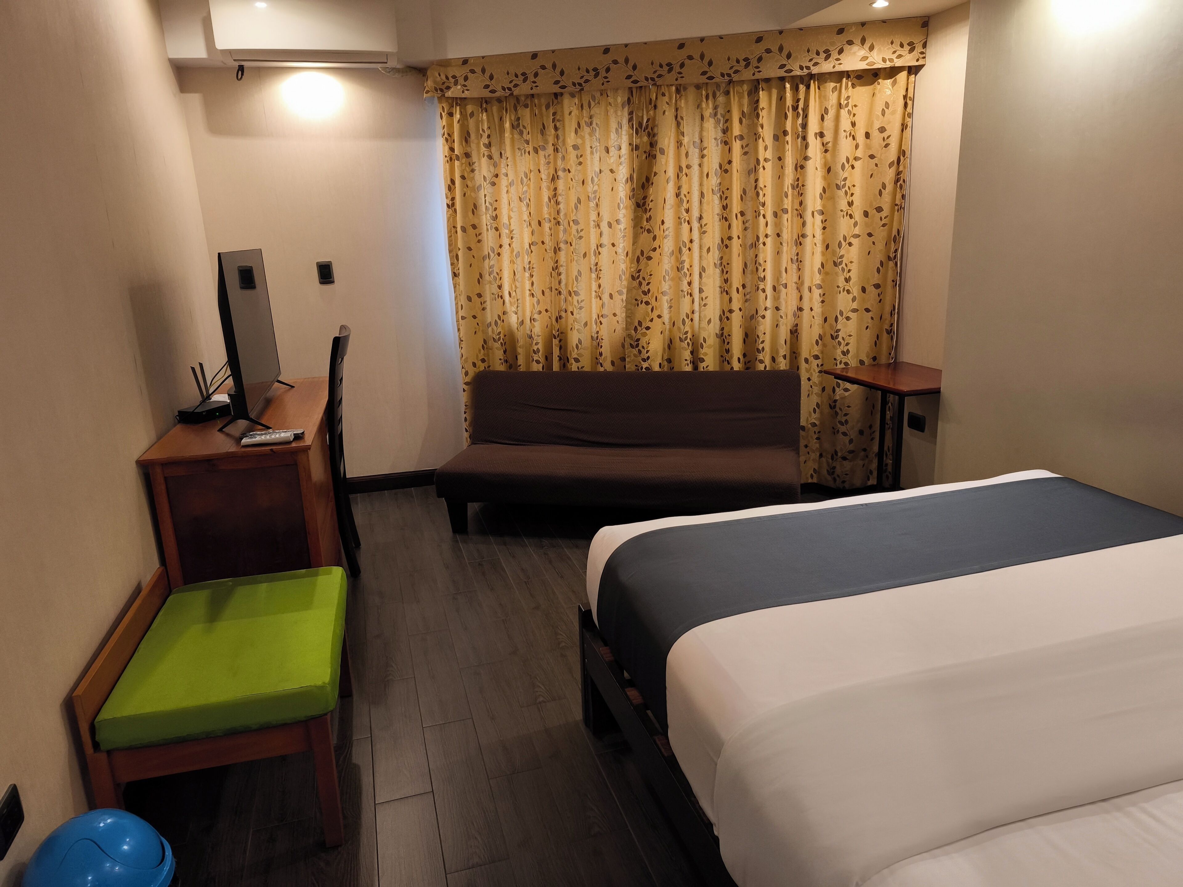 Une chambre d’hôtel avec un lit, un canapé, un bureau avec un ordinateur et une chaise.