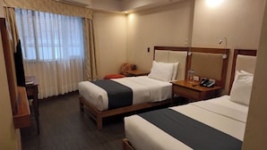 Une chambre d’hôtel avec deux lits, un bureau, une chaise et un téléviseur.