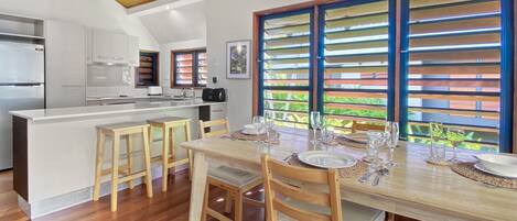 A modern kitchen with white cabinets, a central island, and a dining area with wooden chairs and a table set for four.