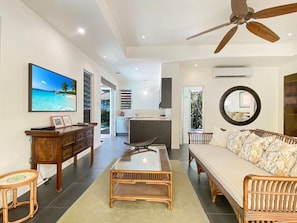 A spacious living area with a sofa, coffee table, and a ceiling fan.