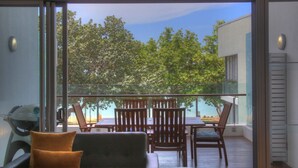 Ein Balkon mit Tisch, Stühlen, einem Grill und Blick auf Bäume und ein Gebäude.