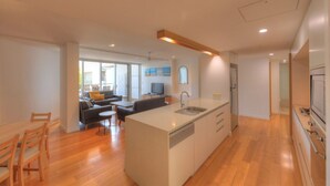 Eine moderne Küche mit Kochinsel, ein Essbereich mit Holzkästen und ein Wohnbereich mit Sofa und Fernseher.