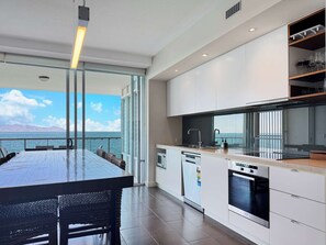 Eine moderne Küche mit Meerblick, ein Essbereich mit Tisch und Stühlen sowie ein Einbauofen.