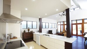 A modern kitchen with a central island, built-in dishwasher, and a large window. - Beached on Magnetic (Picnic Bay)