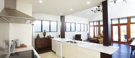 A modern kitchen with a central island, built-in dishwasher, and a large window.