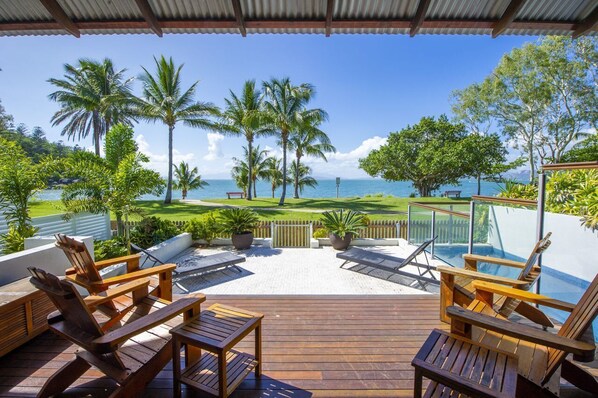 A wooden deck with lounge chairs and a view of the ocean. - Beached on Magnetic (Picnic Bay)