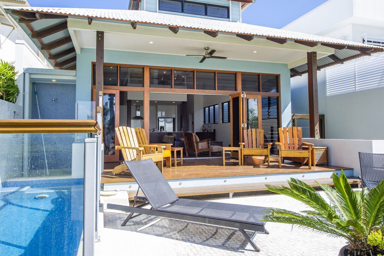 Une maison moderne dotée d’une piscine, d’un espace salon extérieur et d’un patio couvert.
