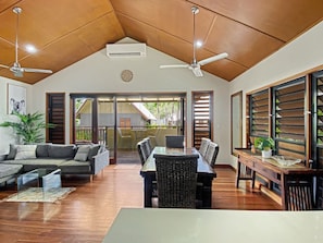A spacious living area with a dining table, sofas, and a ceiling fan. - Pure Magnetic Villa 5, 9 The Esplanade-BOM (Nelly Bay)