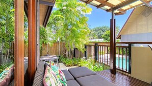 A covered outdoor seating area with a pool in the background.