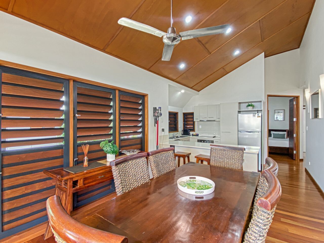 A dining area with a wooden table, chairs, and a ceiling fan.