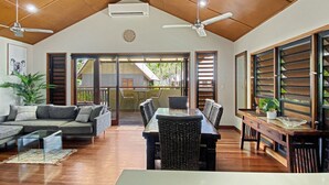A spacious living area with a dining table, sofas, and a ceiling fan.