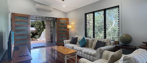 A modern living room with a sofa set, a coffee table, a TV, and a ceiling fan.