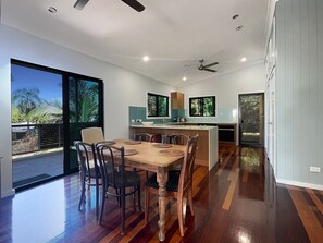 A modern kitchen with a dining area, large windows, and a view of the outdoors. - Deb's Shed (Arcadia)