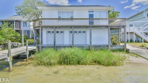 Een tweelaags huis met een balkon, een garage en een houten steiger die in het water reikt.