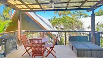 Relax in this outdoor seating area with a table, four chairs, a grill, and a wicker sofa.
