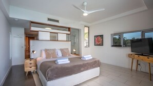 A modern bedroom with a large bed, bedside tables, a ceiling fan, a TV, and a window.