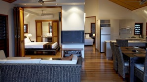 Ein modernes Hotelzimmer mit Bett, Sofa, Fernseher, Küchenzeile und Essbereich.