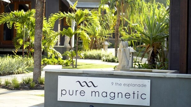 Ein Gebäude mit einem Schild, auf dem 'pure magnetic' steht, und einer Palme im Vordergrund.