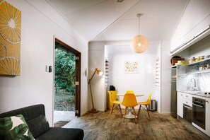 A modern kitchen with white cabinets, a marble countertop, and a hanging pendant light. - The Little Bush Hut (Nelly Bay)