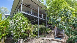 A modern house with a balcony, surrounded by lush greenery and a staircase leading to the upper level. - Horseshoe Bay Vista (Horseshoe Bay)