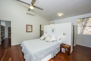 A bedroom with a bed, bedside table, and a ceiling fan.