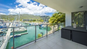 A balcony with a view of a marina, boats, and mountains.