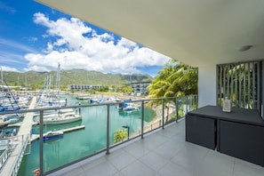 Ein Balkon mit Blick auf einen Yachthafen, Boote und Berge.