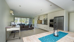A modern kitchen with a large island, a dining area with a blue placemat, and a view of the outside.