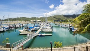 A marina with boats docked, a bridge, and a mountainous landscape in the background.