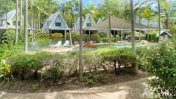 Een resort met meerdere bungalows, een zwembad en weelderige tropische begroeiing.