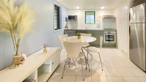 Een moderne keuken met witte kasten, een roestvrijstalen koelkast en een eethoek met een witte tafel en stoelen.